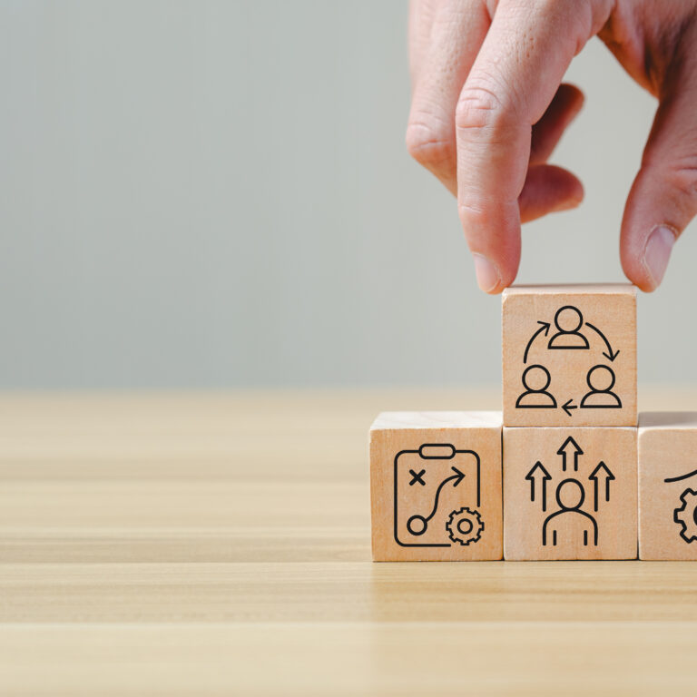 change management process concept with hand arranging wooden blocks showing strategy, growth, learning, leadership, and teamwork icons, symbolizing organizational transformation, business improvement